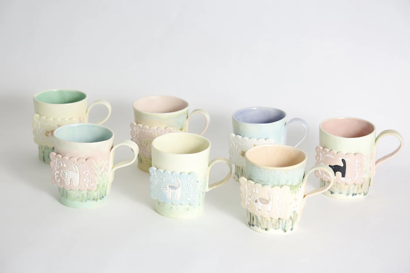 A group of pastel ceramic mugs with illustrated scenes