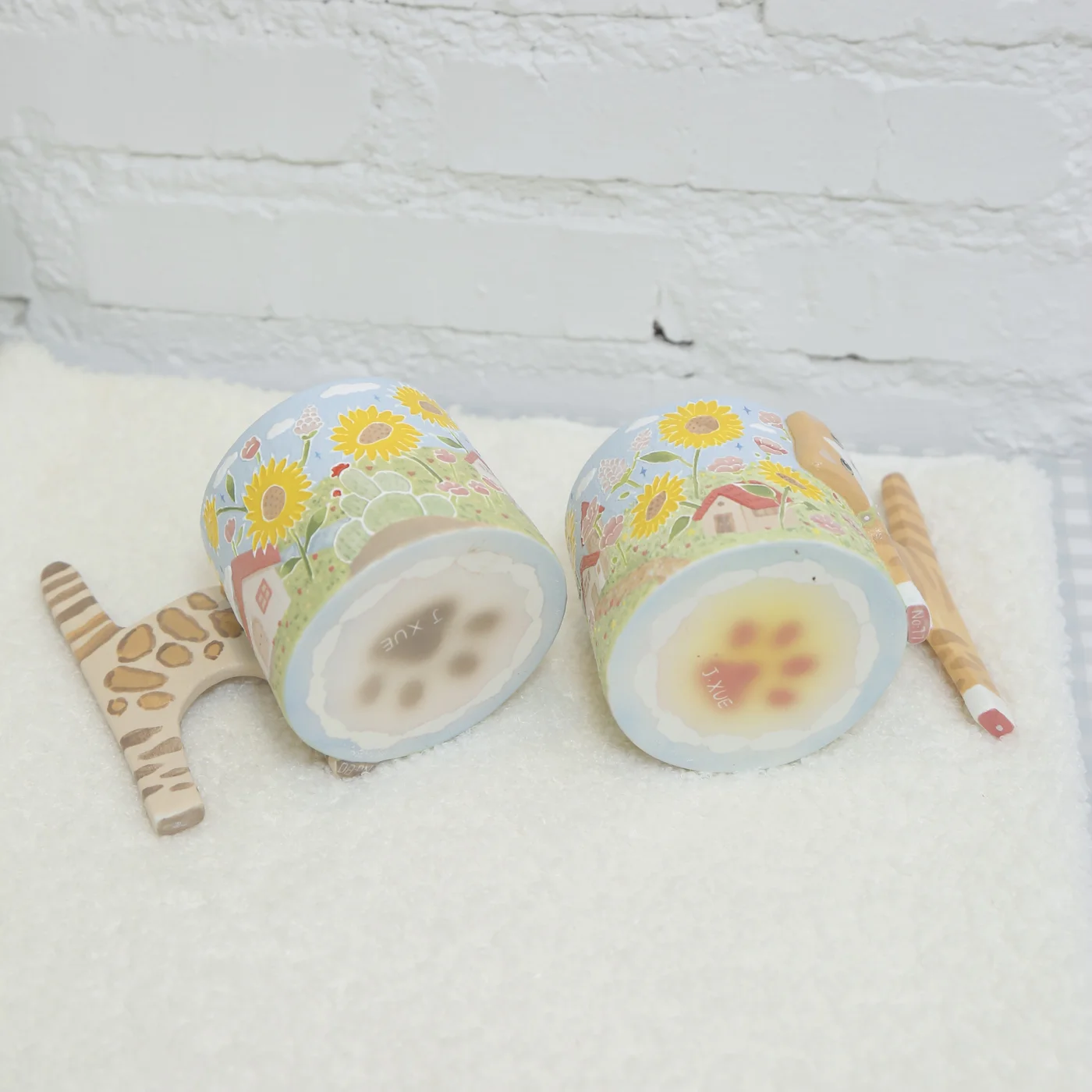 Two real Hollow Valley cat cups showing their colourful paw-print bases